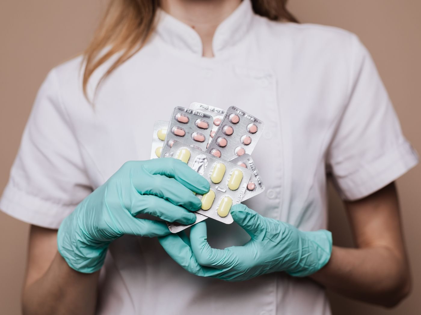 Gloved hands checking blister packs against the batch documentation