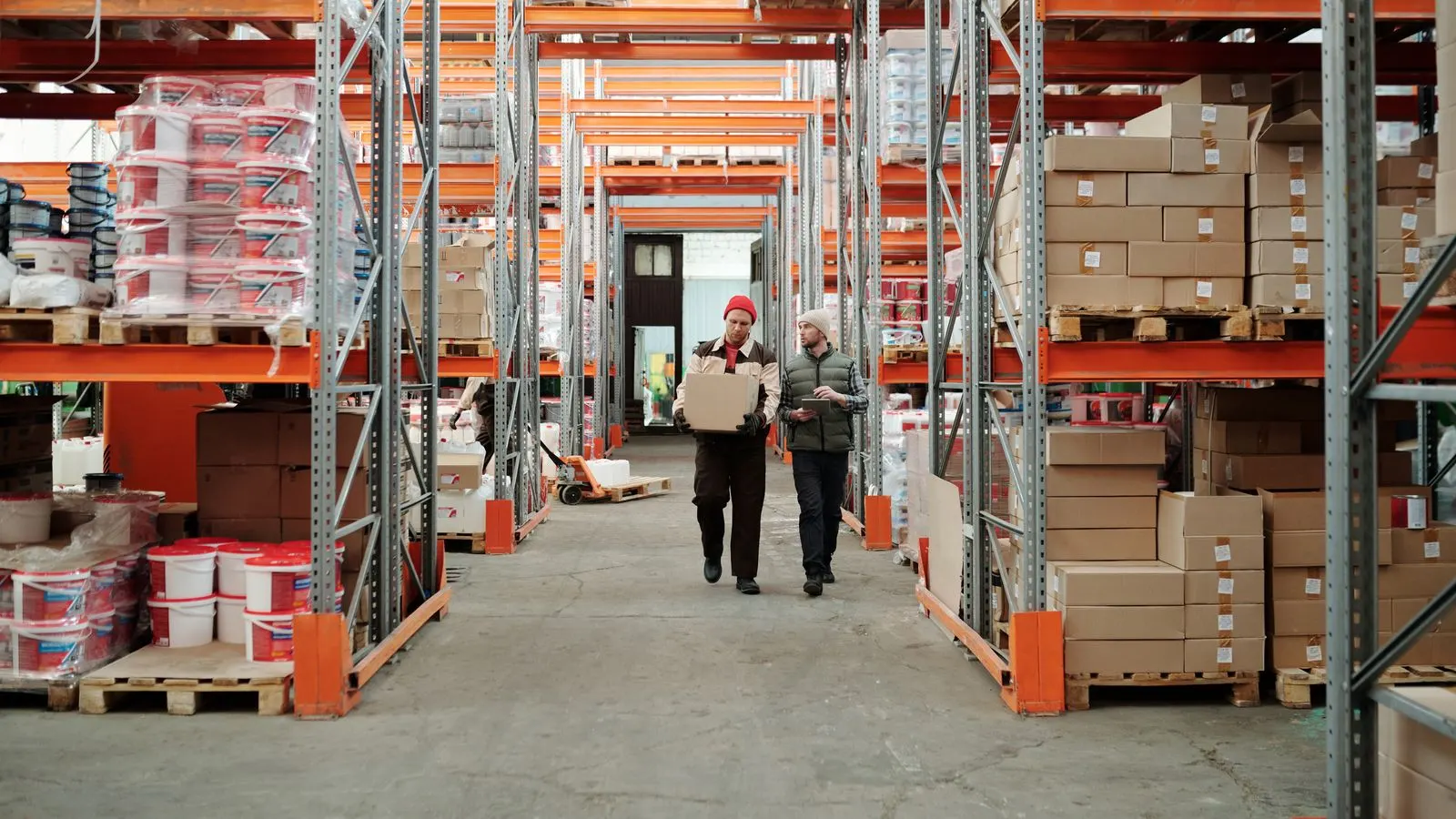 Warehouse staff handling a packed consignment beside stocked shelves